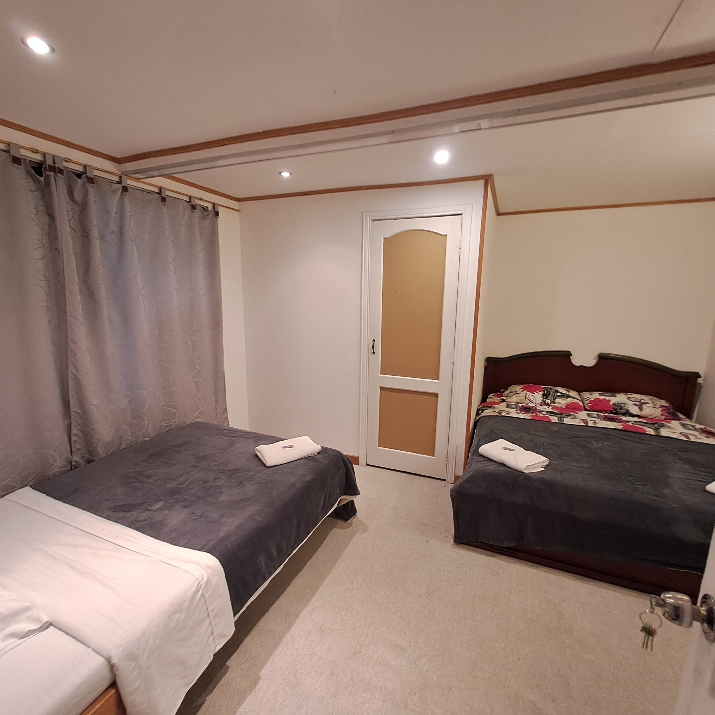 A bedroom with two beds, a door, and a mirror.