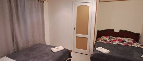 Un dormitorio con dos camas, una puerta y un espejo.