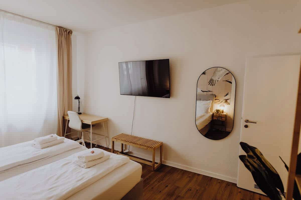 Una habitación de hotel con una cama, un escritorio, un televisor y un espejo.