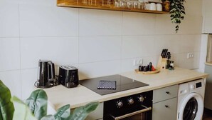 A kitchen with a countertop, a stove, a toaster, a kettle, a sink, and a washing machine. - Staylight | City Loft in the Old Town | Balcony (Hildesheim)