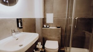 A modern bathroom with a white sink, toilet, and glass-enclosed shower. - Staylight | City Loft in the Old Town | Balcony (Hildesheim)