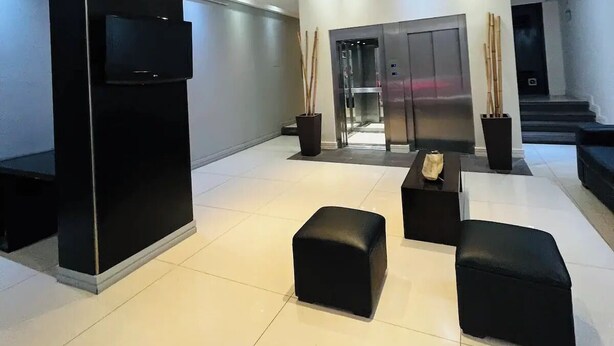 Eine moderne Lobby mit hoher Decke, eingelassener Beleuchtung, einer großen schwarzen Säule und einem Empfangsbereich.