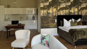 Un interior moderno con comedor, sala de estar con sofá y un cuadro, y un dormitorio con cama y mesita de noche.