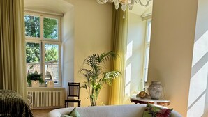 Una sala de estar con un sofá, sillones, una mesita y una araña.