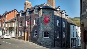 A historic building with a prominent red lion emblem, stone facade, and multiple windows. - The Red Lion (Knighton)