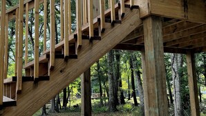 Un escalier en bois menant à une plateforme située dans une zone boisée.