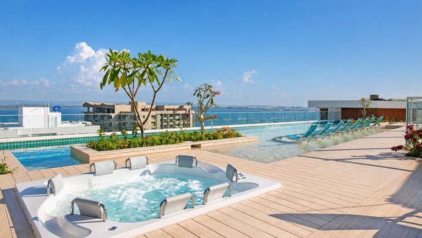 Ein Pool auf dem Dach mit Whirlpool, Liegestühlen und Meerblick.