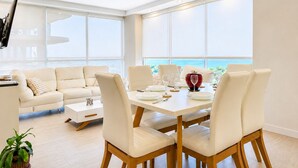 Ein modernes Wohnzimmer mit Essbereich, großen Fenstern und Meerblick.