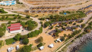 An aerial view of a coastal resort with multiple bungalow-style accommodations, a central building with a red roof, and a swimming pool. - Adria Family Zone B 6+1 (Klenovica)