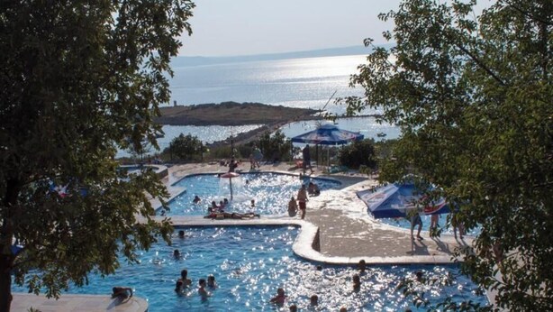 Un área de piscina con varias piscinas y gente nadando.