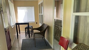 Ein Zimmer mit Esstisch, zwei Stühlen, einer Couch und einem roten Sessel.
