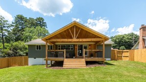 A wooden house with a front porch, a small attached garage, and a fenced backyard. - Lakeview Retreat | Family-Friendly · Near Downtown (Macon)