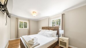A hotel room with a wooden bed, a nightstand, a lamp, and a ceiling light. - Lakeview Retreat | Family-Friendly · Near Downtown (Macon)