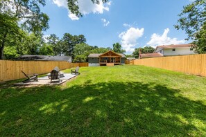 A backyard with a wooden fence, a grassy lawn, and a house with a porch. - Lakeview Retreat | Family-Friendly · Near Downtown (Macon)