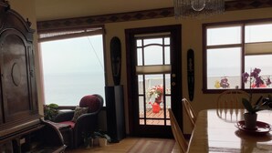 A dining area with a view of the ocean, a wooden dining table, chairs, a rug, and a cabinet. - Vacation Home For Rent - Ainsworth BC (Ainsworth)