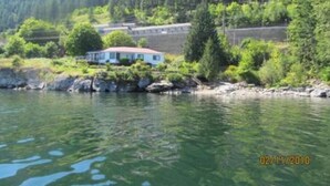 A house by a lake with a forest in the background. - Vacation Home For Rent - Ainsworth BC (Ainsworth)