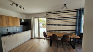 Eine moderne Küche mit Essbereich, ausgestattet mit einem großen Fenster, einer Wand mit Muster und einem Holzesstisch.
