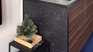 Une cuisine moderne avec des meubles en bois foncé, un pare-feu en carreaux blancs et un plan de travail en marbre noir.