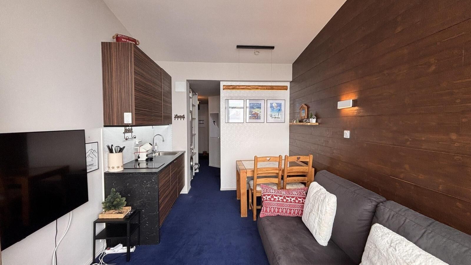 A compact living space with a kitchenette, a dining area, and a seating area with a sofa and chairs.