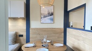 Un comedor con una mesa redonda, sillas, una lámpara colgante y un cuadro en la pared.
