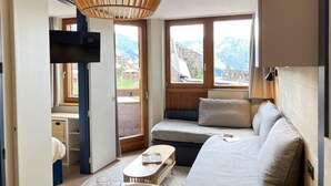 Un espacio habitable compacto con sofá, una mesita y televisor.
