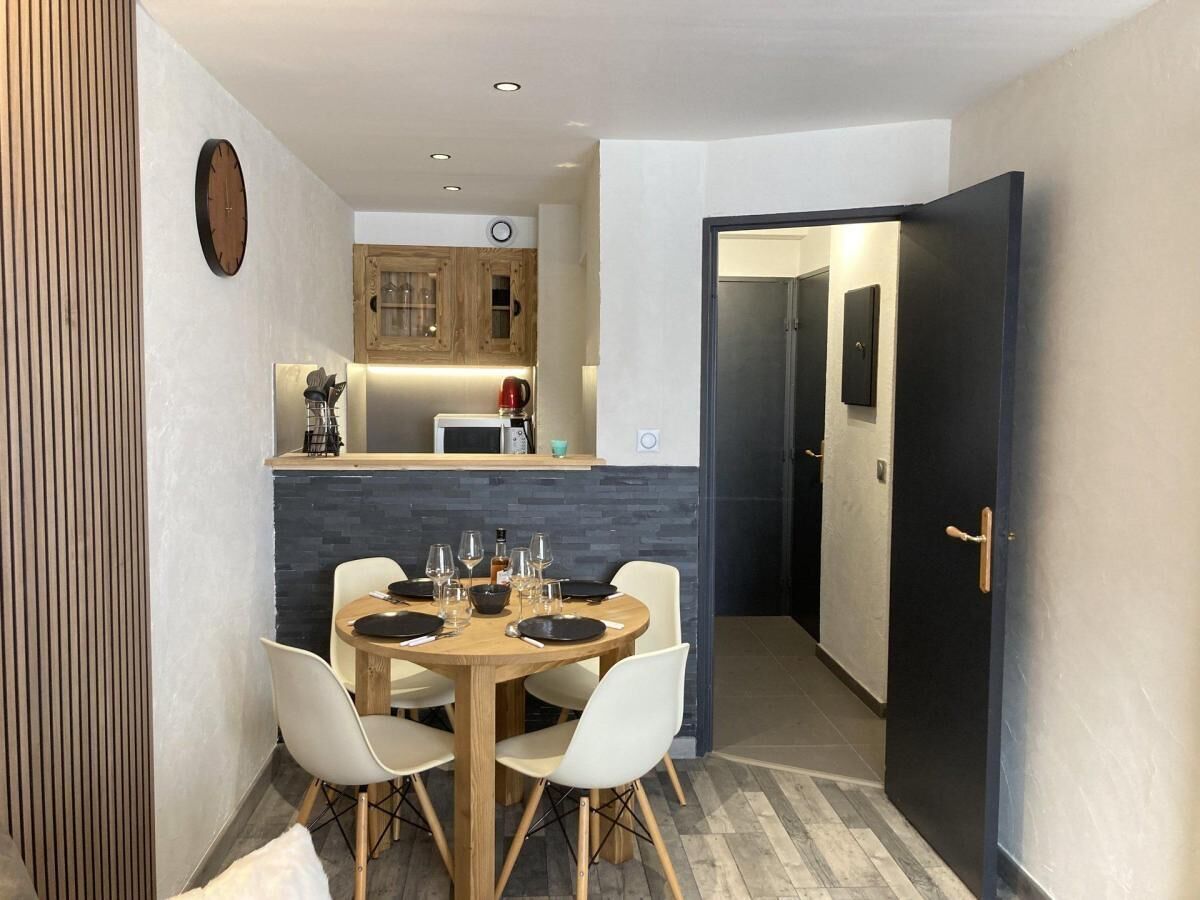 A compact kitchen with modern appliances and a dining area with a round table and white chairs.