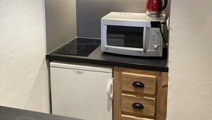 A compact kitchen with a microwave, a kettle, and a small refrigerator.