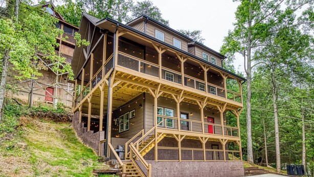 Eine mehrstöckige Holzhütte mit einem Balkon im zweiten Stock, umgeben von Bäumen.