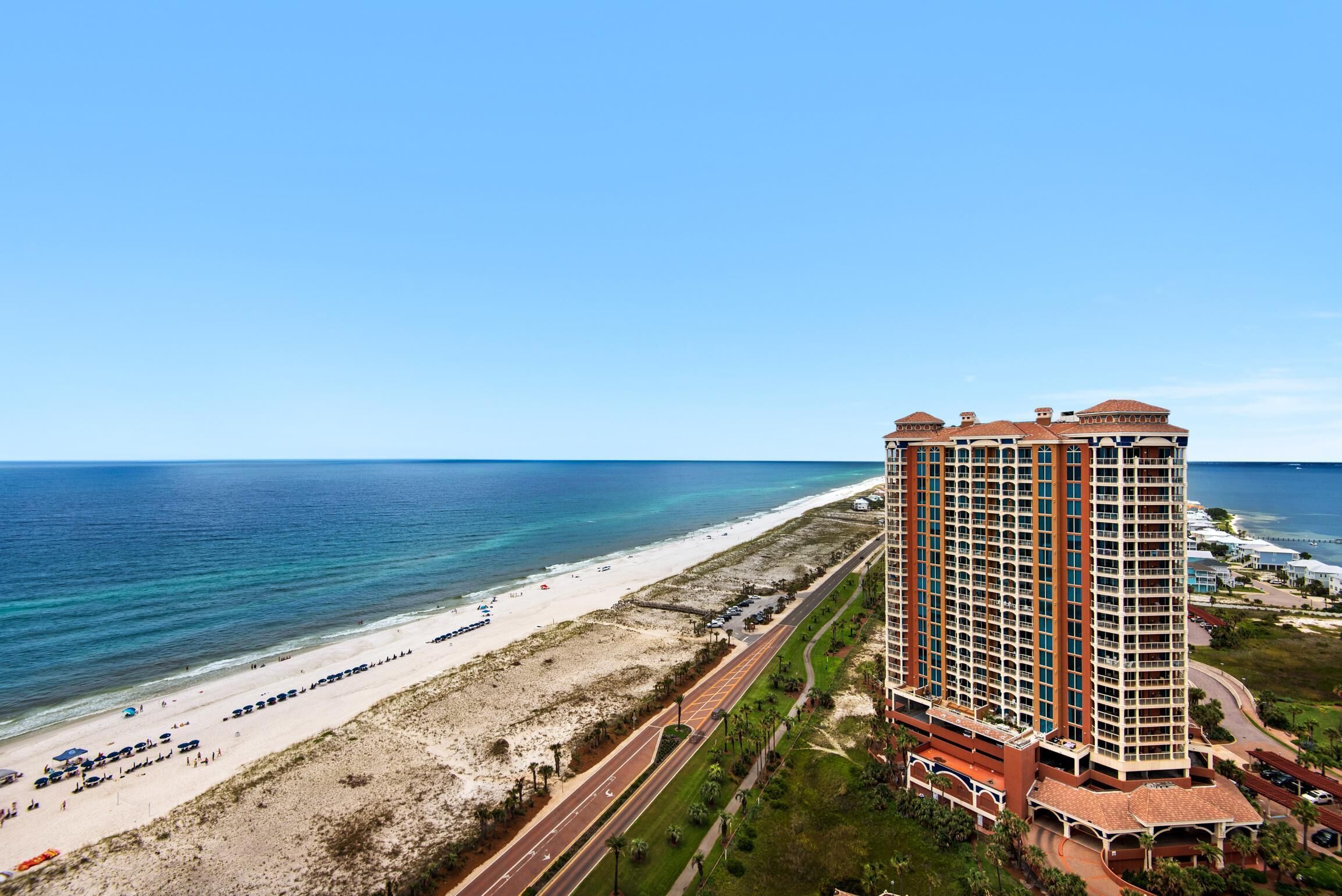 A high-rise hotel with multiple balconies overlooking a beach and ocean.