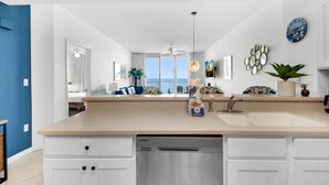 A modern kitchen with a dishwasher, a sink, and a ceiling fan. - Summerwind West 1203 (Navarre)