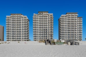 Three high-rise buildings with balconies, a sandy beach in the foreground, and a clear blue sky. - Summerwind West 1203 (Navarre)