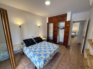 Ein Schlafzimmer mit Bett, Nachttischlampen, einem Kleiderschrank und einem durch eine offene Tür sichtbaren Badezimmer.