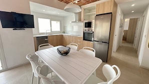 Una cocina moderna con armarios blancos, un refrigerador de acero inoxidable y un horno empotrado.