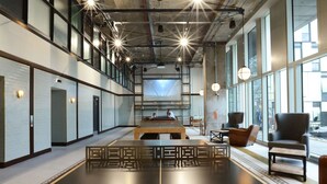 A modern interior with a long table, seating, and large windows. - Chapter Kings Cross - Campus Accommodation (London)
