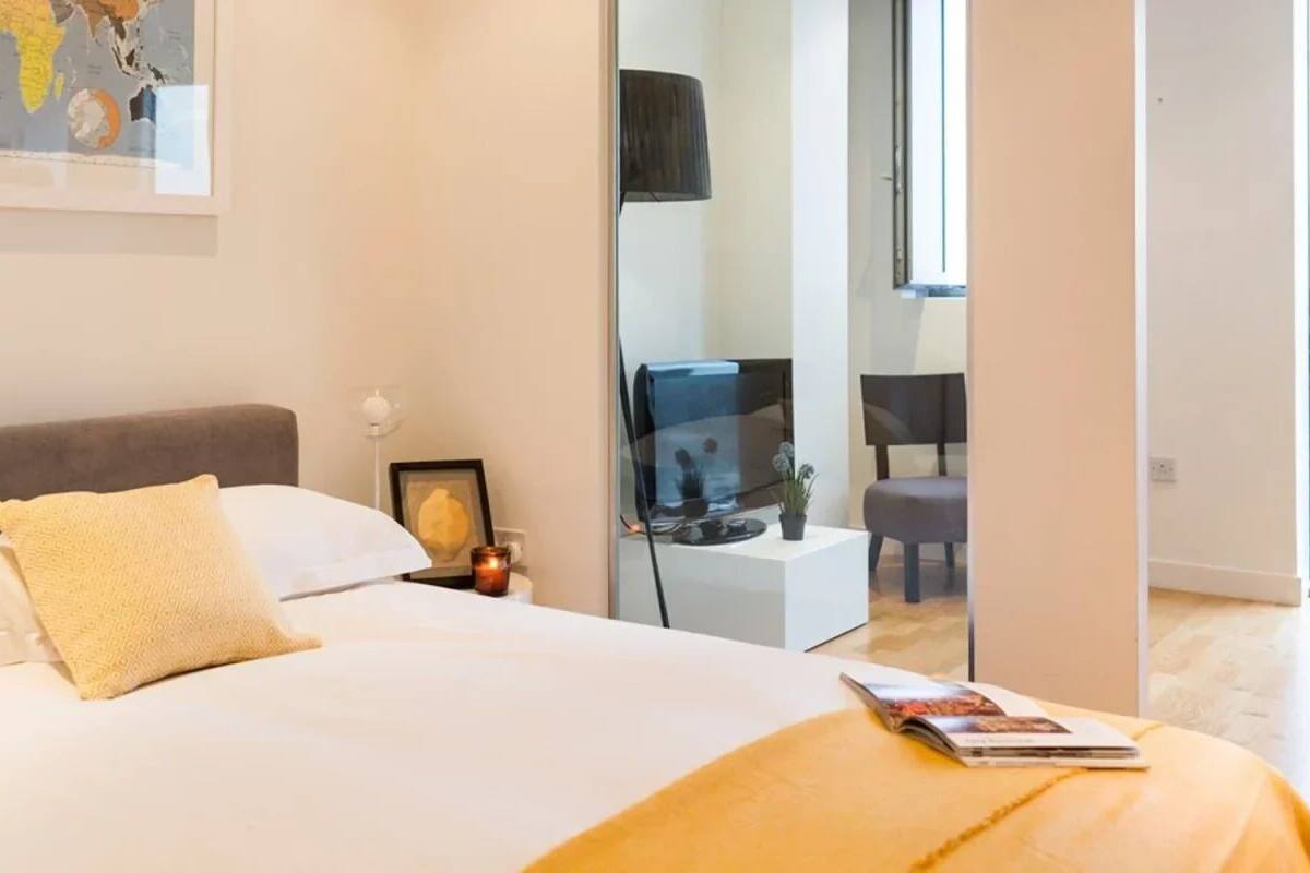 A modern bedroom with a large bed, a bedside table with a lamp, and a framed picture on the wall.
