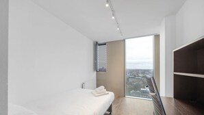 A modern hotel room with a large window, a bed, a wardrobe, and a city view. - Chapter Kings Cross - Campus Accommodation (London)
