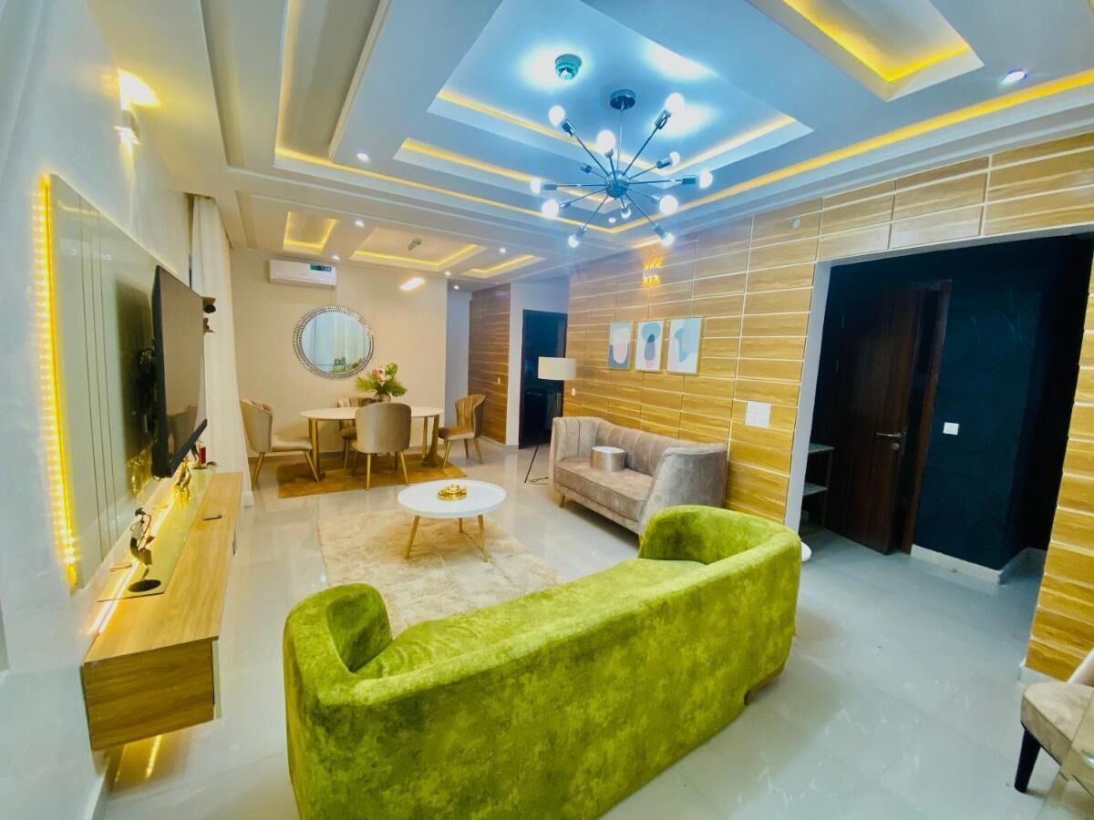Un salon moderne avec un canapé vert, une table basse ronde et un téléviseur posé sur un meuble en bois.