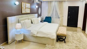 Une chambre moderne avec un grand lit, des lampes de chevet, une petite table et un banc.