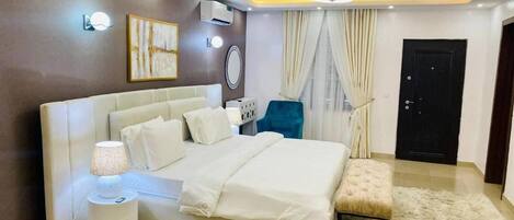 A modern bedroom with a large bed, bedside lamps, a small table, and a bench.