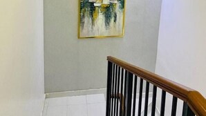 Un escalier avec une rampe en bois et un luminaire fixé au mur.