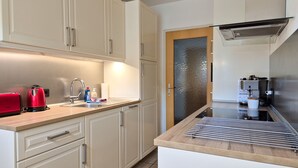A modern kitchen with a stainless steel sink, a red toaster, and a coffee machine. - Penthouse Summer & Winter Fun 4, roof terrace (Zell am See)