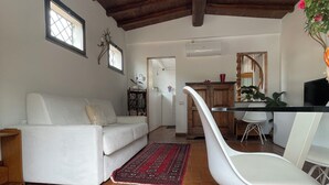 Un'ampia zona giorno con un divano bianco, un tappeto rosso decorato e una poltrona bianca.