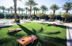A poolside area with artificial grass, lounge chairs, and umbrellas. - Desert Blue Studio Unit! 1 Mile from Las Vegas Strip! (Las Vegas)
