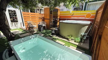 Un patio trasero con piscina, terraza de madera y jacuzzi.