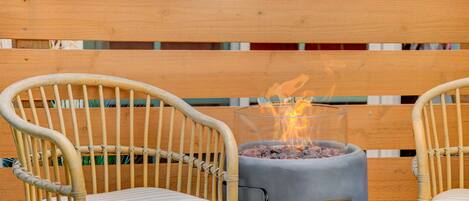 Un patio con dos sillas de mimbre y una parrilla de carbón.