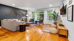 Un salón moderno con un sofá gris, una mesa de centro de madera y un mueble aparador de madera con objetos decorativos.