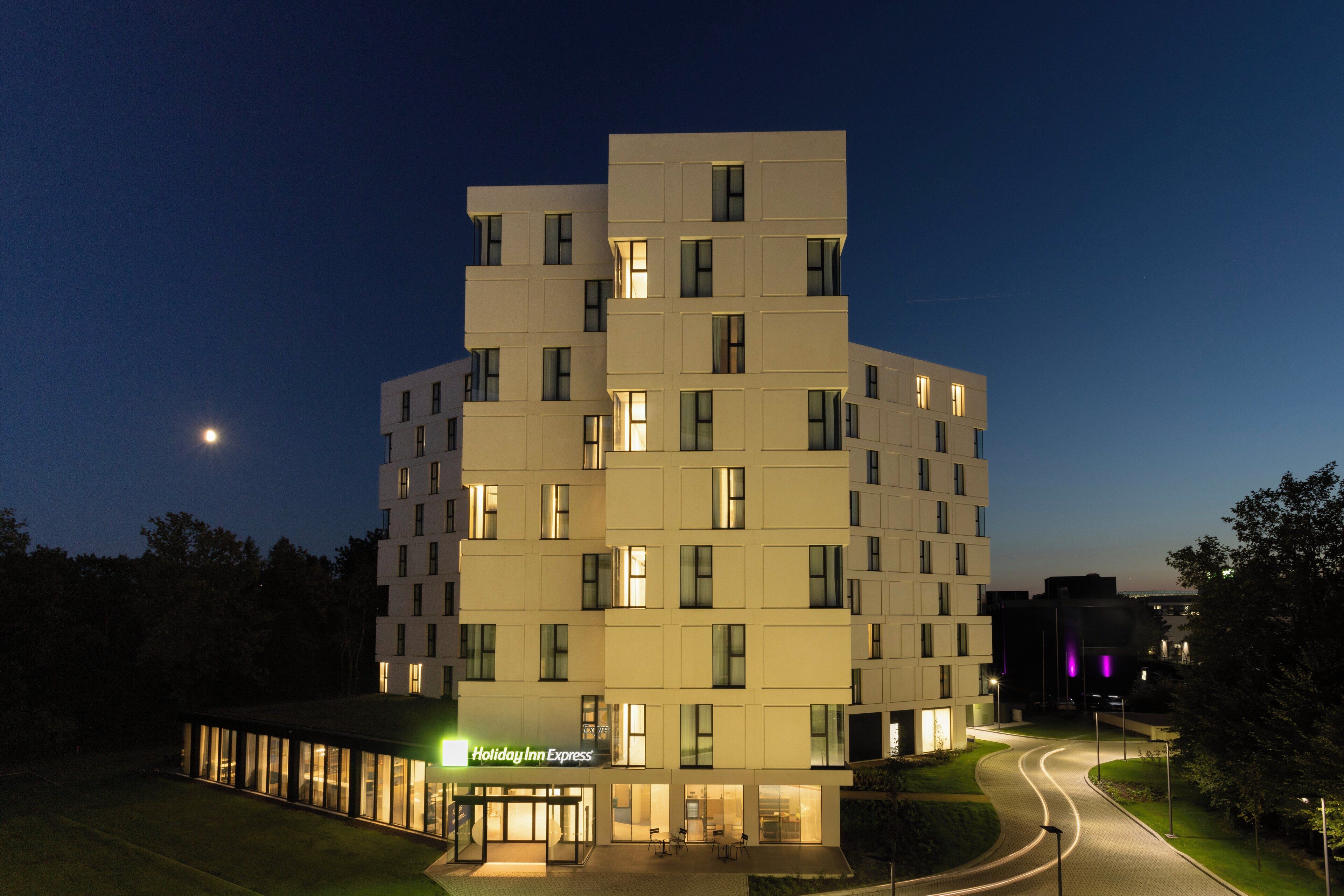 A modern hotel with a unique architectural design, featuring multiple levels and a well-lit entrance.