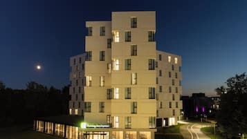 A modern hotel with a unique architectural design, featuring multiple levels and a well-lit entrance.