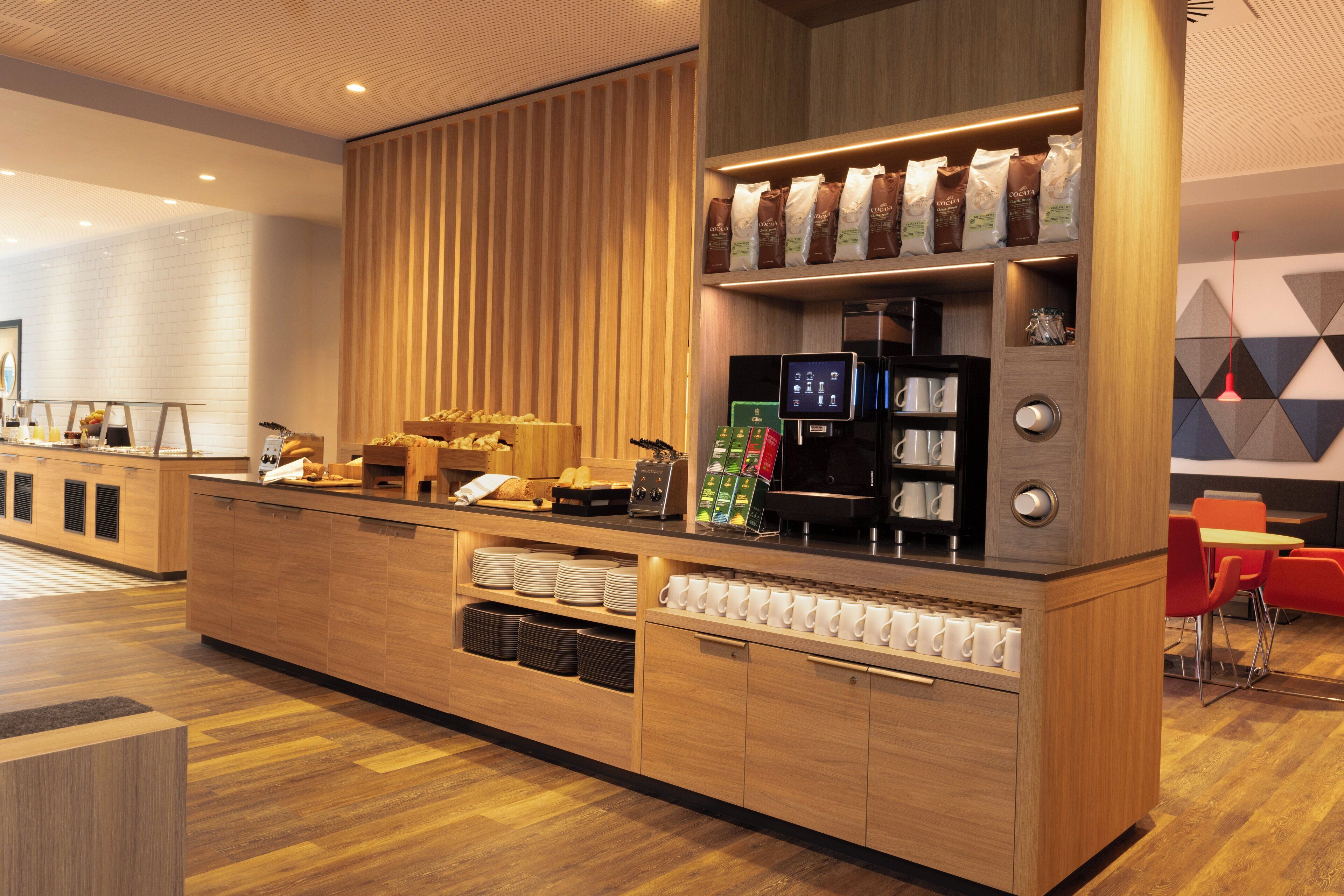 Een moderne koffiehoek met een houten toonbank, koffieapparaten en diverse zakken koffie.