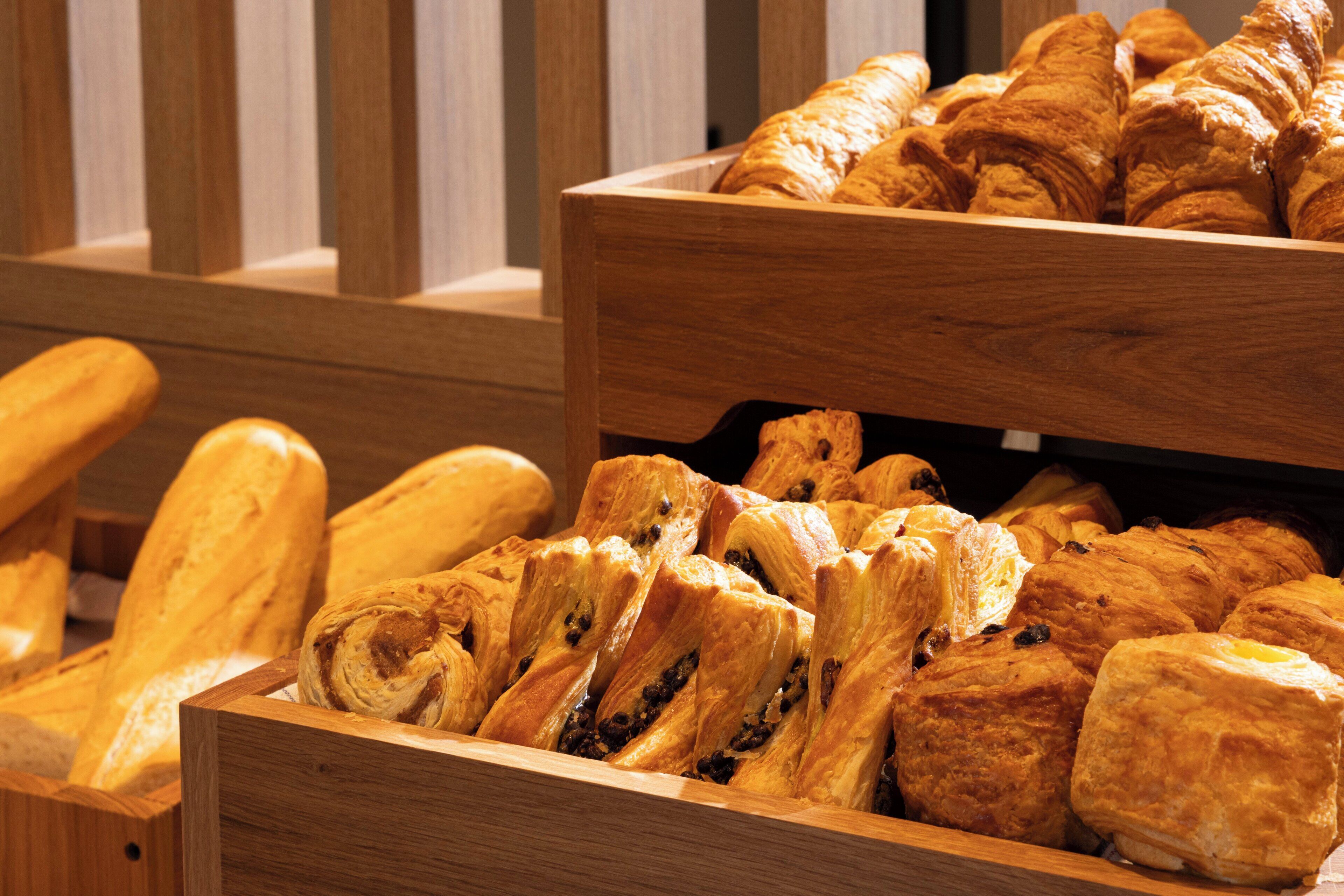 Une vitrine en bois remplie de différents types de pain et de pâtisseries.